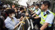 A pro-democracy protester ties up a yellow ribbon to one of the fences blocking the access to Liaison Government Office during the rally in Hong Kong (9 November 2014)