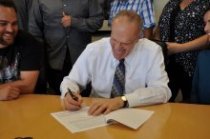 Chancellor Kim Wilcox jokes with UCR veteran students as he signs the Yellow Ribbon paperwork.